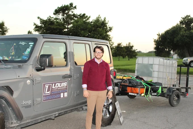 Person standing beside the Louis Fleet Appearance vehicle and mobile trailer